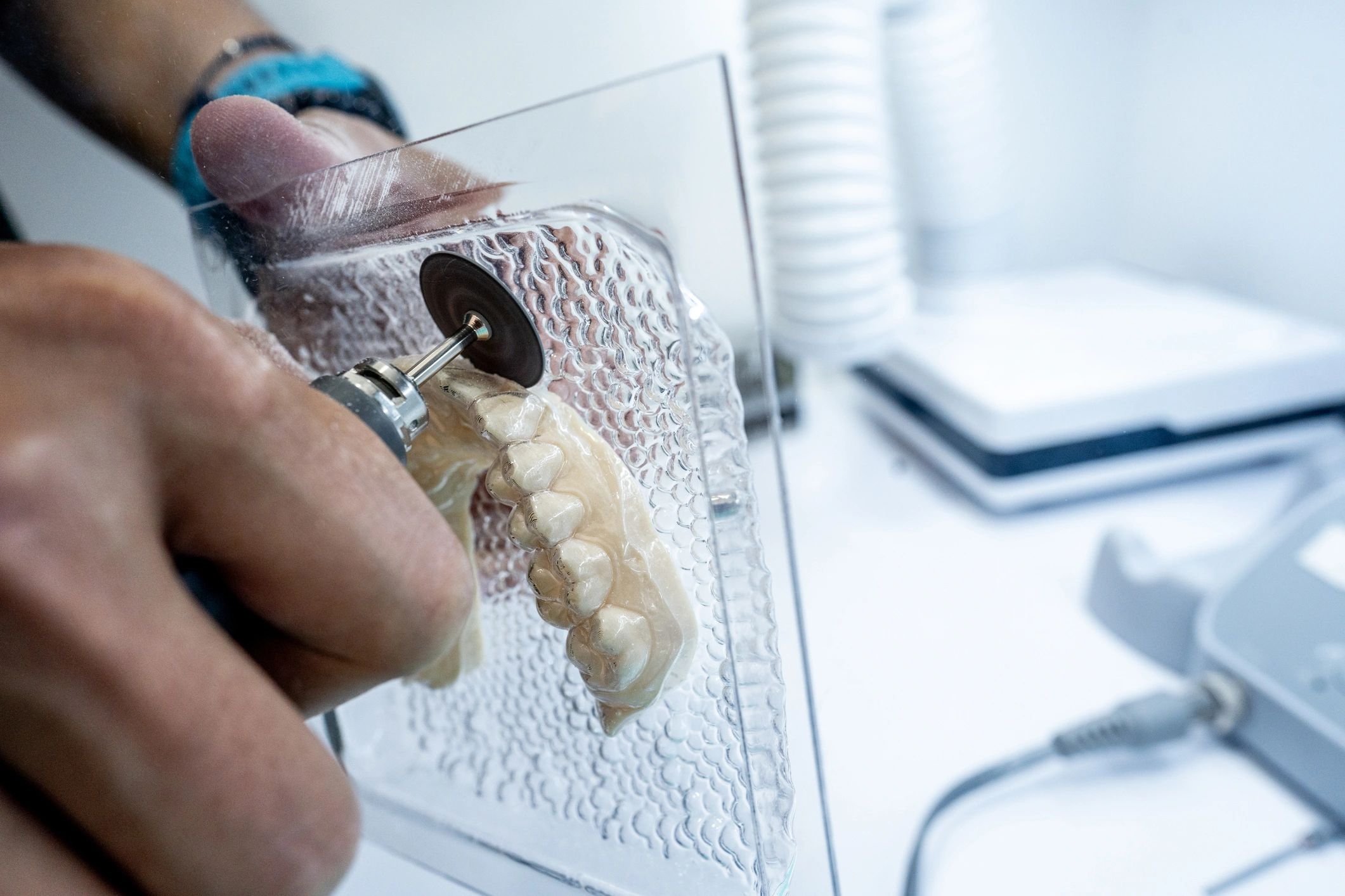 Close-up of a dental technician trimming a denture mold in a laboratory